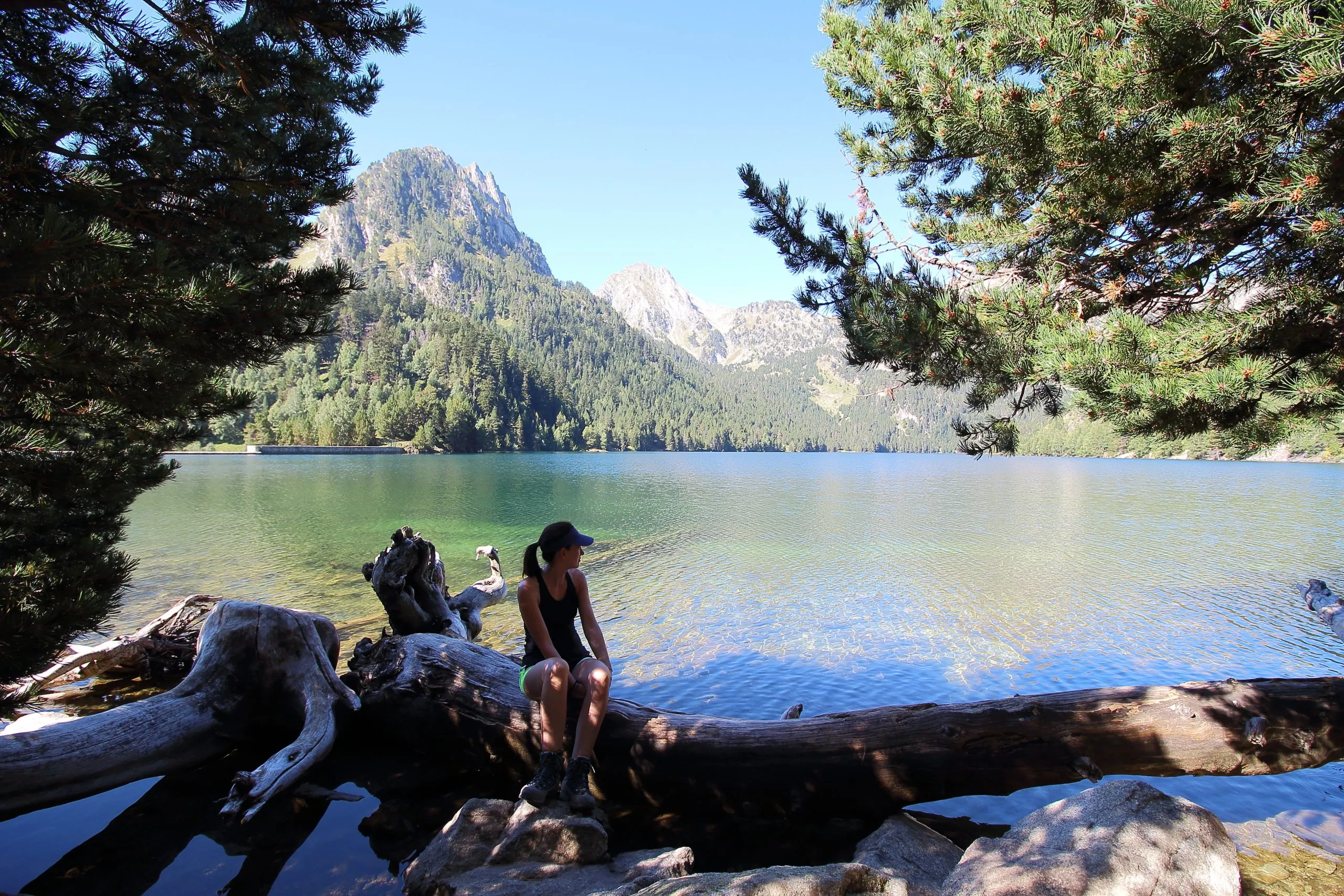 Young beautiful woman restin in Estany de Sant Maurici lake, after a long mrning hike in the Aiguestortes National Park, Pyreness mountains, Catalonia, Spain